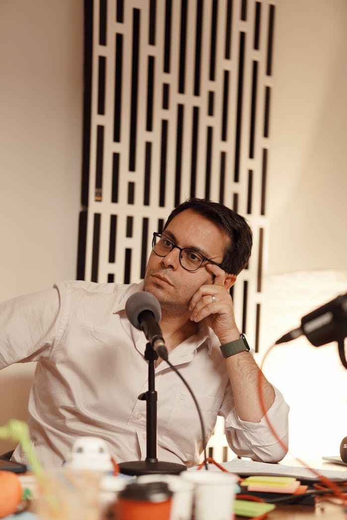 Young man recording a podcast in a professional studio setting with a microphone.